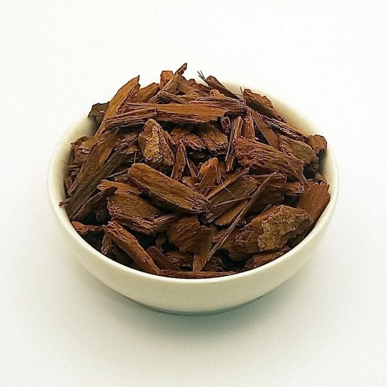 Cut sassafras root bark pieces, warm red-brown, in a white bowl